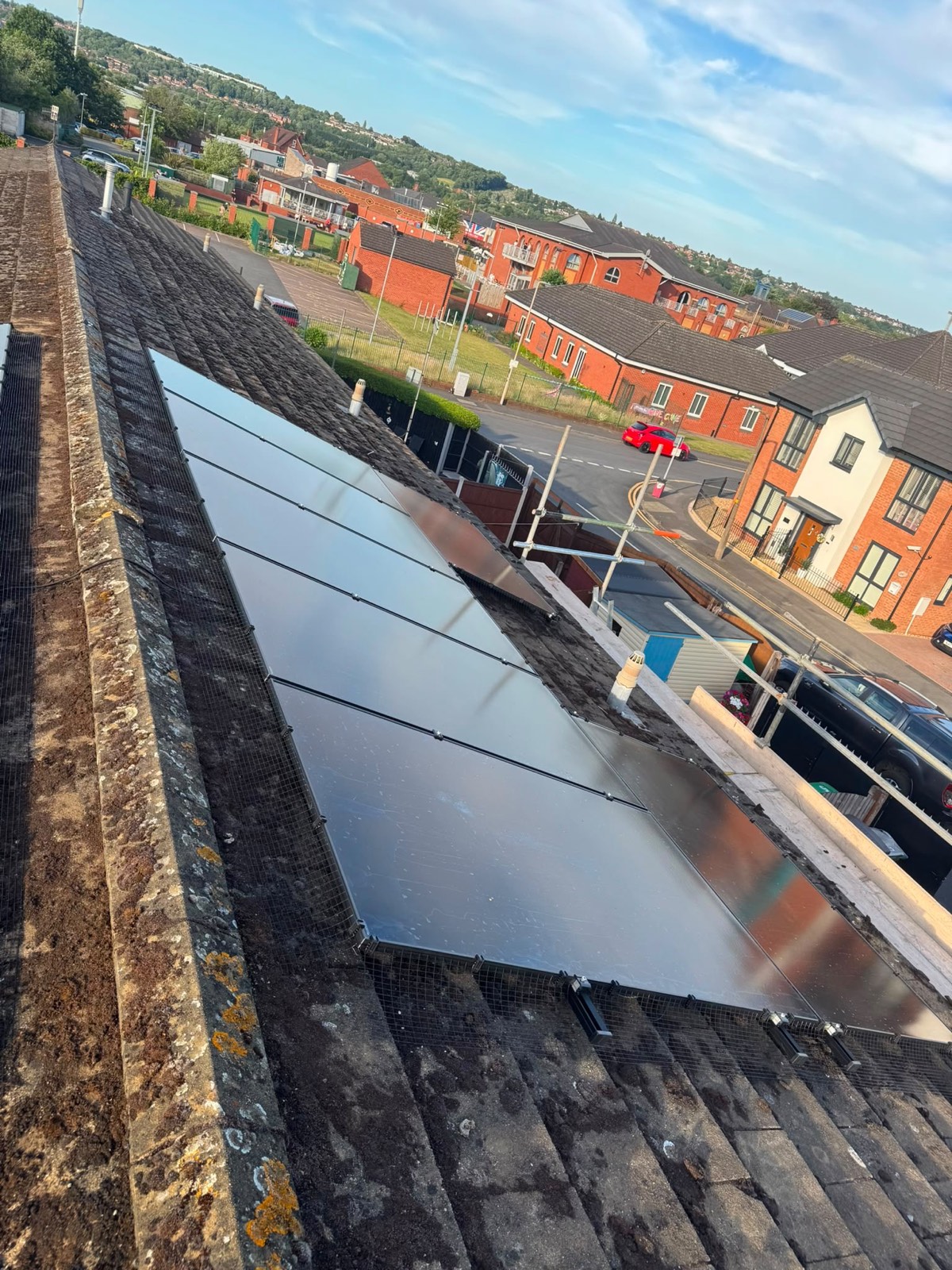 All-black solar panels installed along a tiled roof with bird protection mesh fitted around the edge of the array