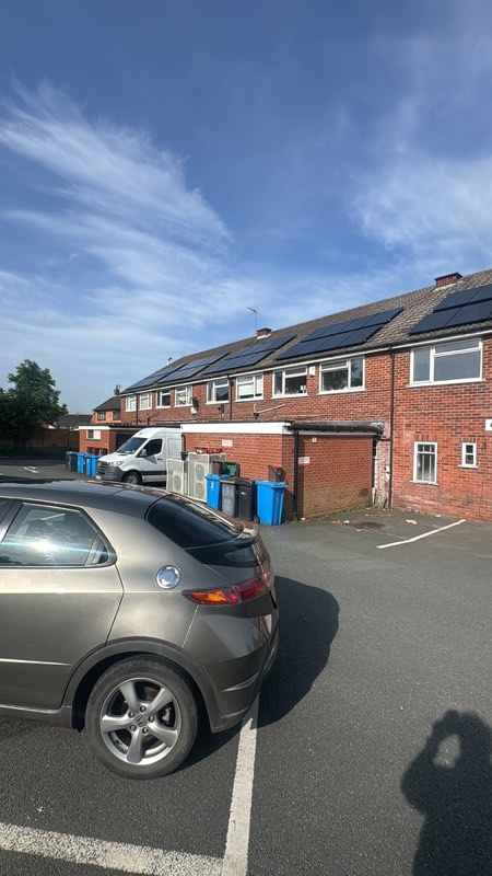 A row of terraced houses with solar panels installed across several adjoining roofs